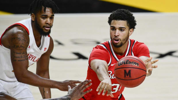 Ohio State forward passes the ball while being defended by Maryland forward Donta Scott in a game.